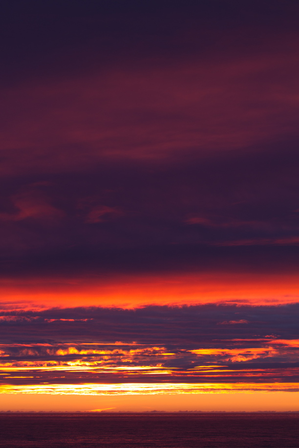 A spectacular Arctic sunset illuminates the cloud layers above.